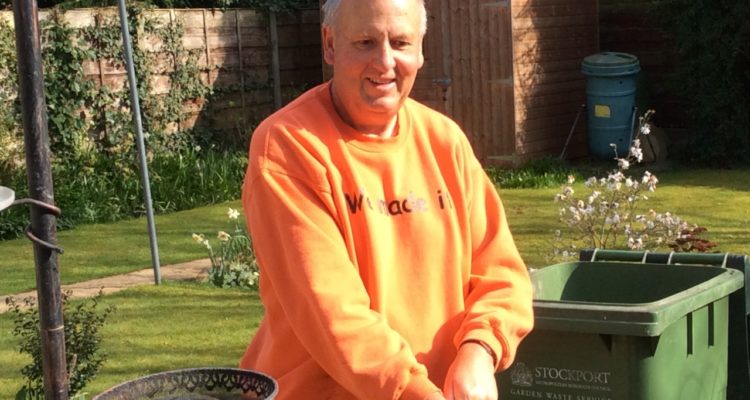 Derek in his garden wearing gardening gloves.