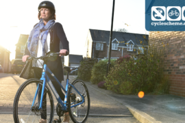 A woman wearing a helmet walking with a blue bike