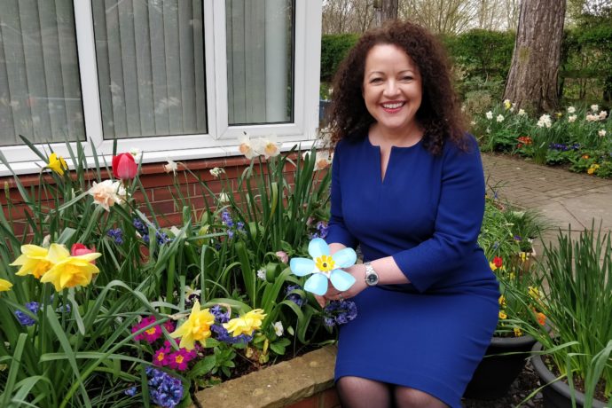 Rachel McMillan sat in the hospice gardenholding a metal forget-me-not